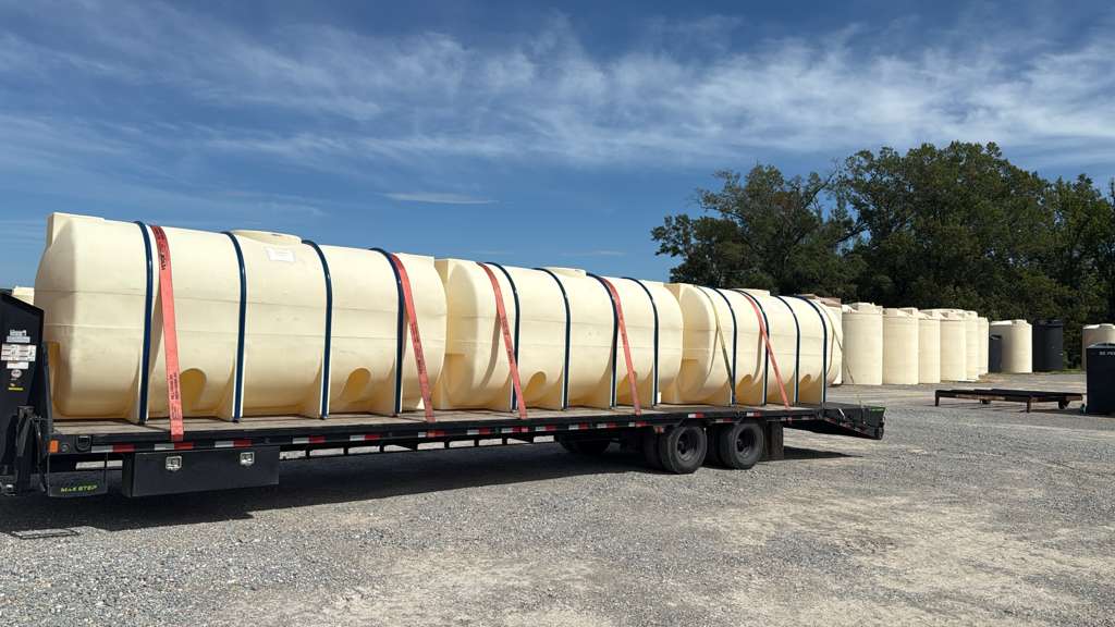 A Load Genius Logistics flatbed loaded with tanks, strapped and ready for transport